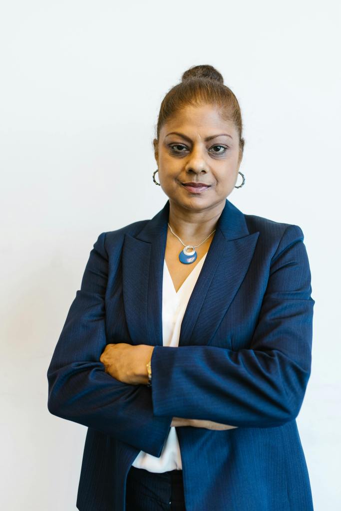 Confident woman in a suit with arms crossed, expressing leadership and professionalism in an office setting.